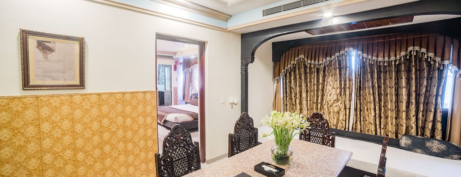 Queen Room featuring a long table with chairs, and a dark curtain backdrop. - Hotel Ashok Nagpur