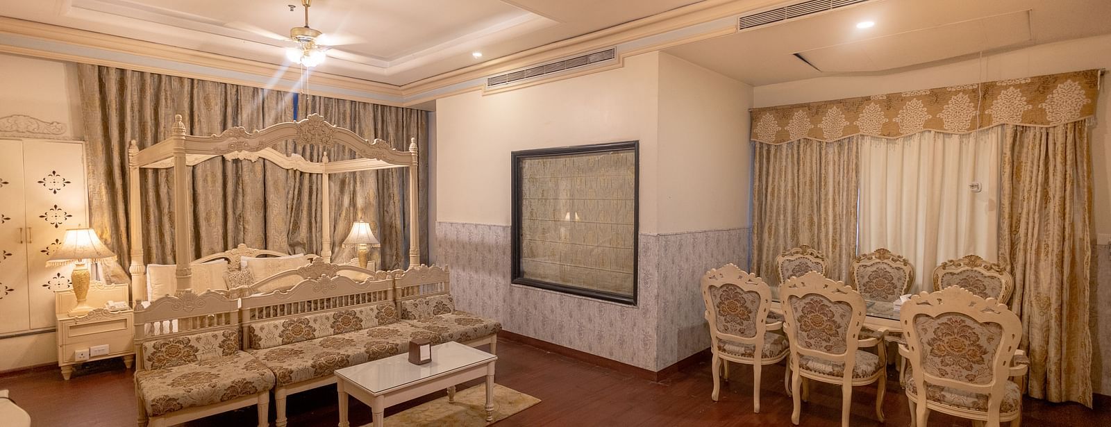 King Suite eaturing a seating area with a sofa and coffee table, a dining area with four chairs, and neutral-toned decor.- Hotel Ashok Nagpur