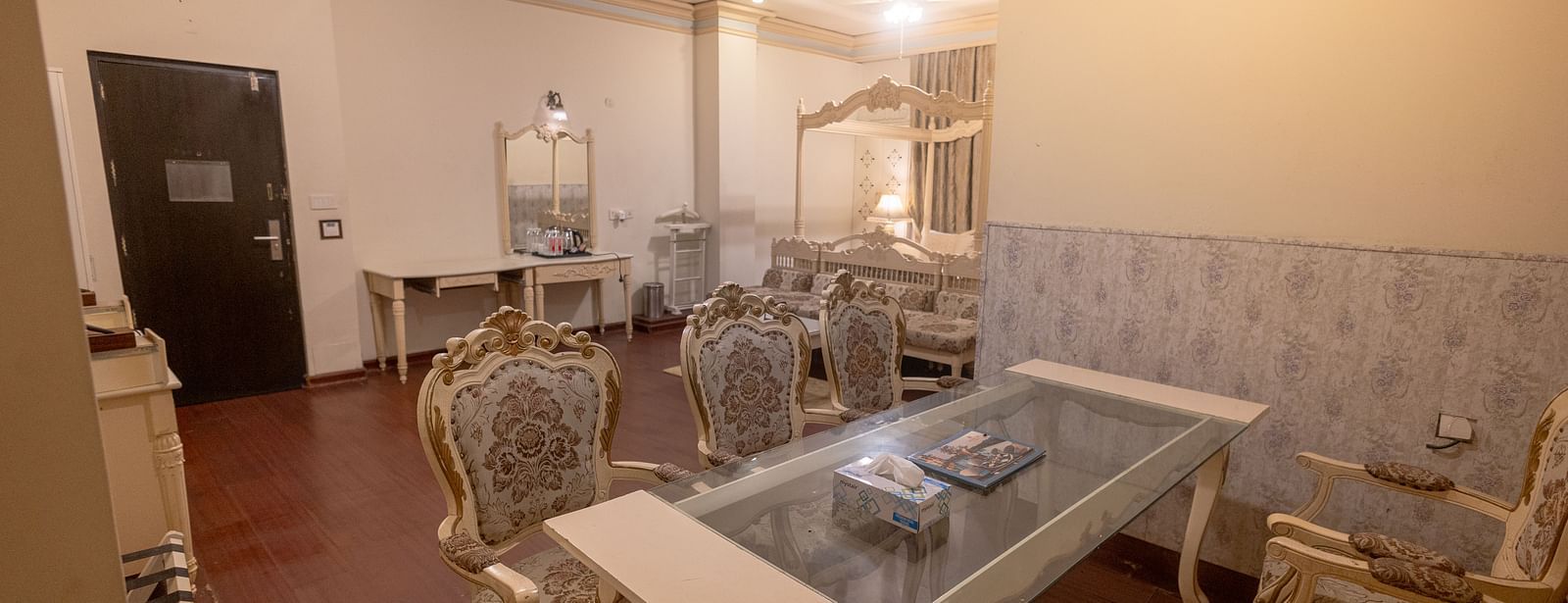 King Suite featuring a glass-topped coffee table and upholstered chairs with wooden frames.- Hotel Ashok Nagpur