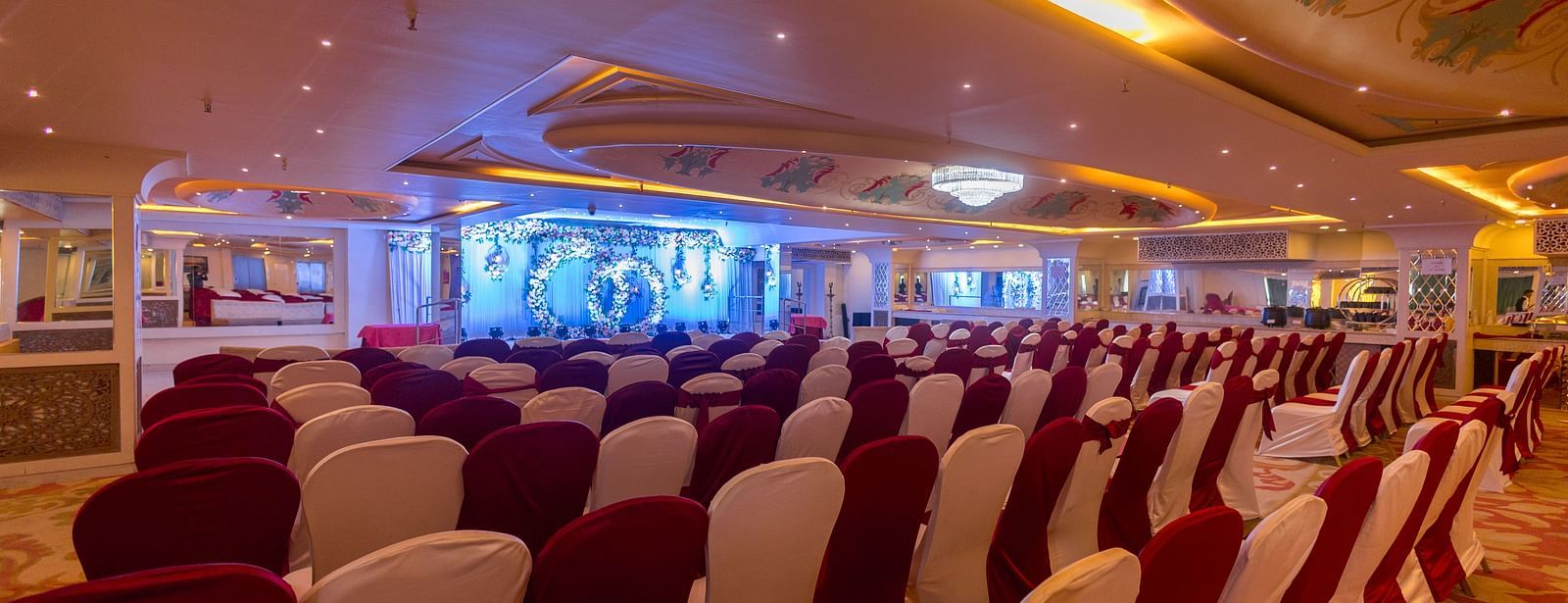 Samrat featuring rows of chairs arranged facing a stage with a screen.