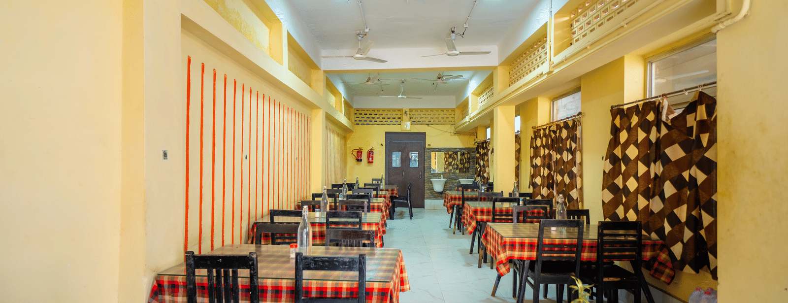 Hotel dining hall showing multiple tables set up under overhead ceiling fans - Hotel Dolphin Puri