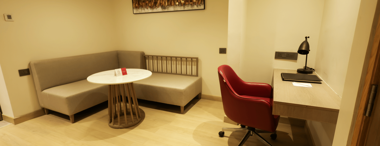 Compact work area with desk, red chair, and casual round table seating at Ramada by Wyndham Sonipat Murthal