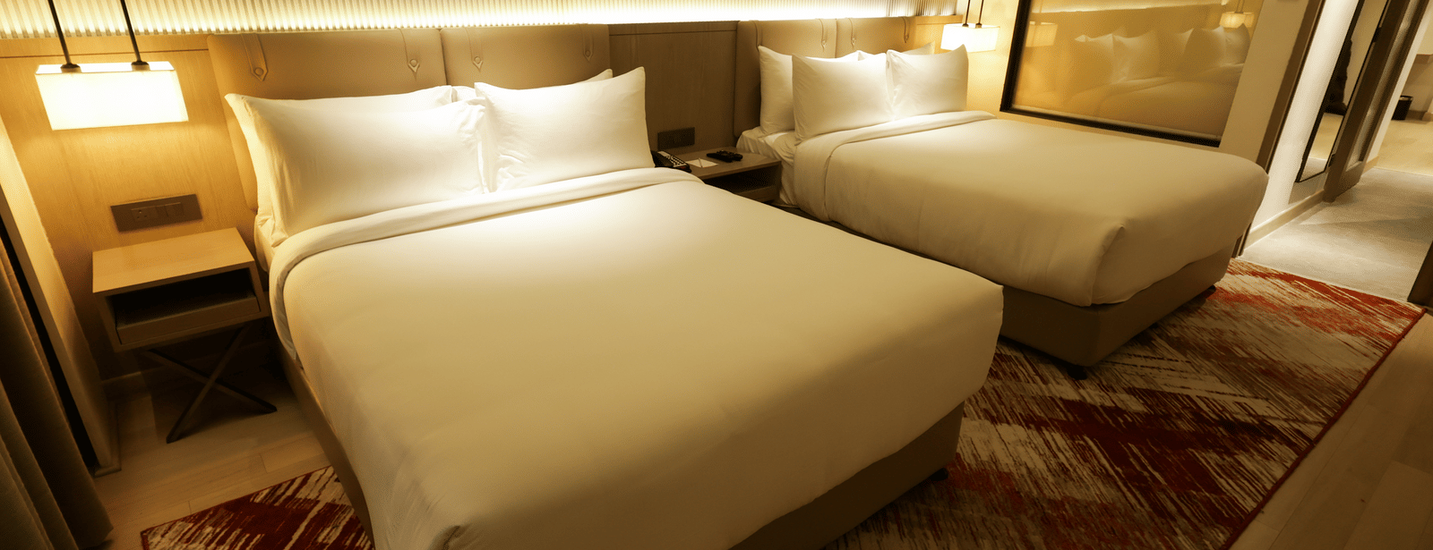 Warmly lit bedroom with wooden furnishings and red-patterned carpet at Ramada by Wyndham Sonipat Murthal