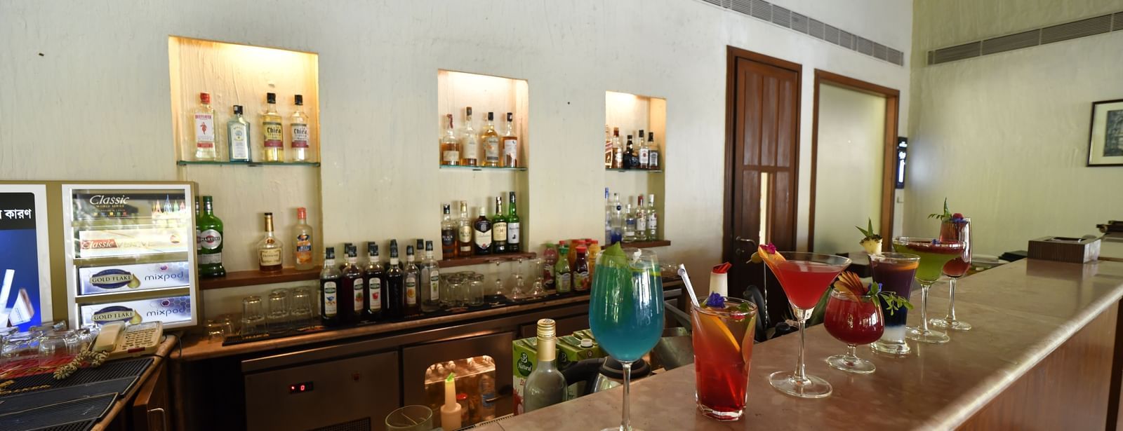 A bar counter with drinks and bottles neatly arranged, at Vedic Village Spa Resort.