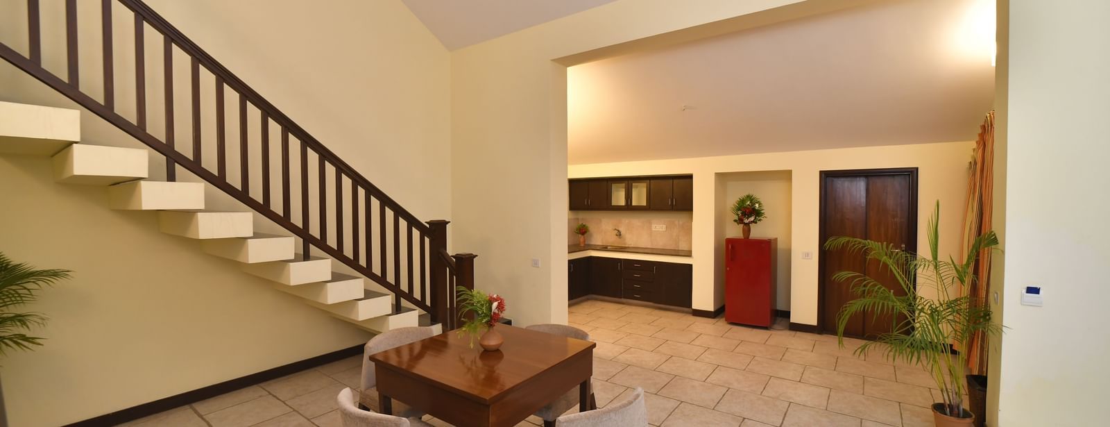 A spacious interior features a grand staircase leading to an upper level, with a seating area below | Green Villa