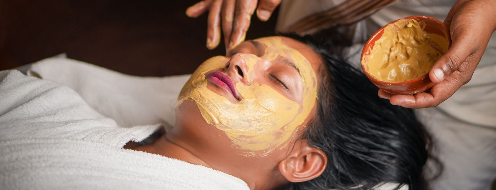 Facial mask application in Vedic Village Spa Resort, featuring a person receiving a natural face pack.