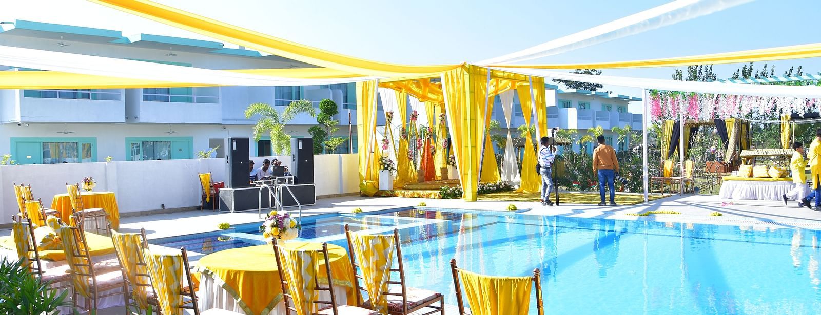 Poolside wedding seating arrangement with bright yellow drapery at Vedikant Resorts The Mallard Corbett.