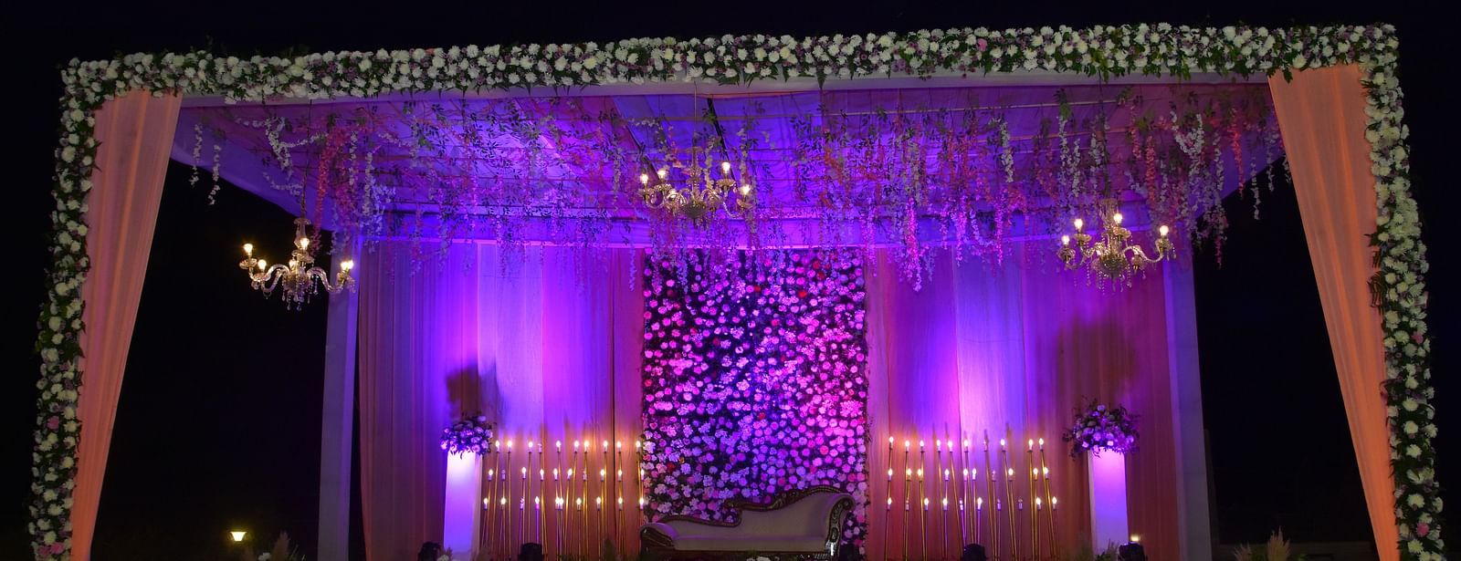 Nighttime wedding stage decor with purple lights at Vedikant Hotels & Resorts.
