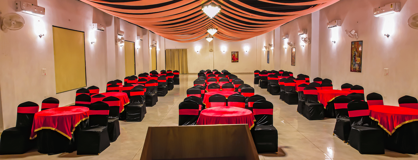 Another view of an empty banquet hall at Vedikant Resorts The Mallard Corbett displays rows of chairs and tables under a decorated ceiling.