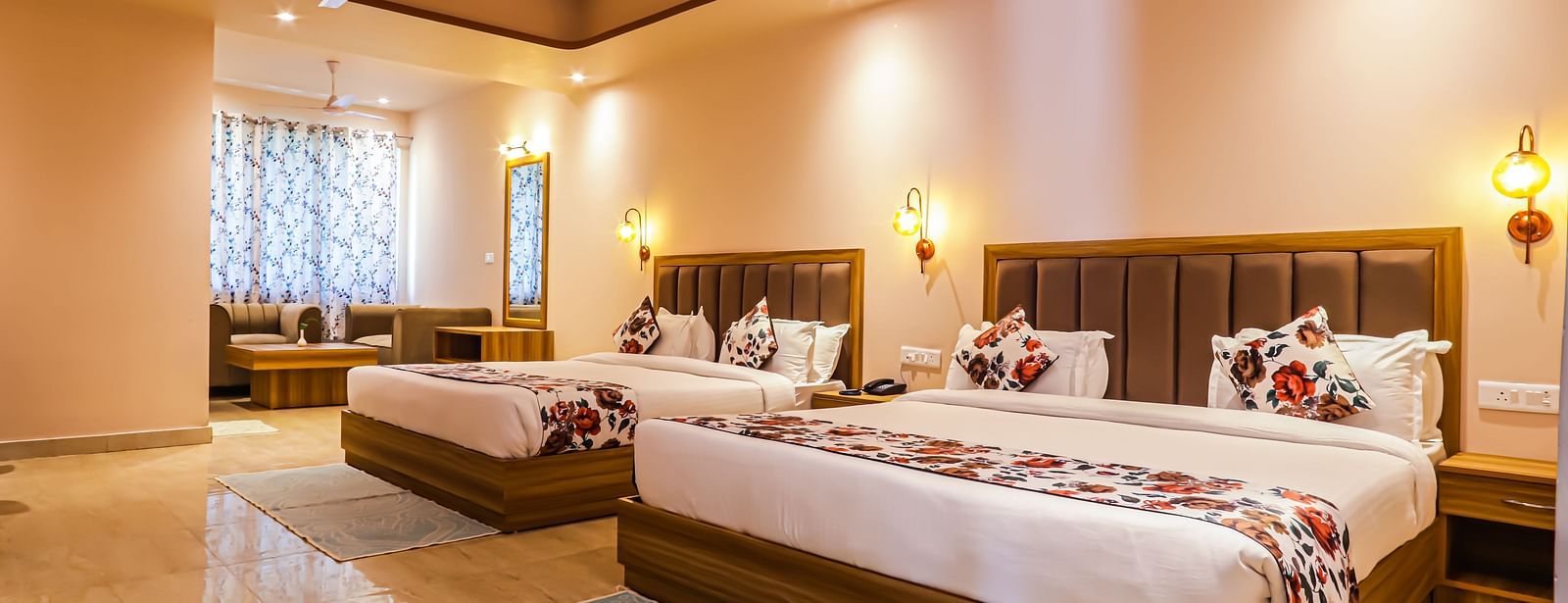 A comfortable bedroom at Vedikant Resorts The Mallard Corbett offers beds, a seating arrangement, and warm lighting.