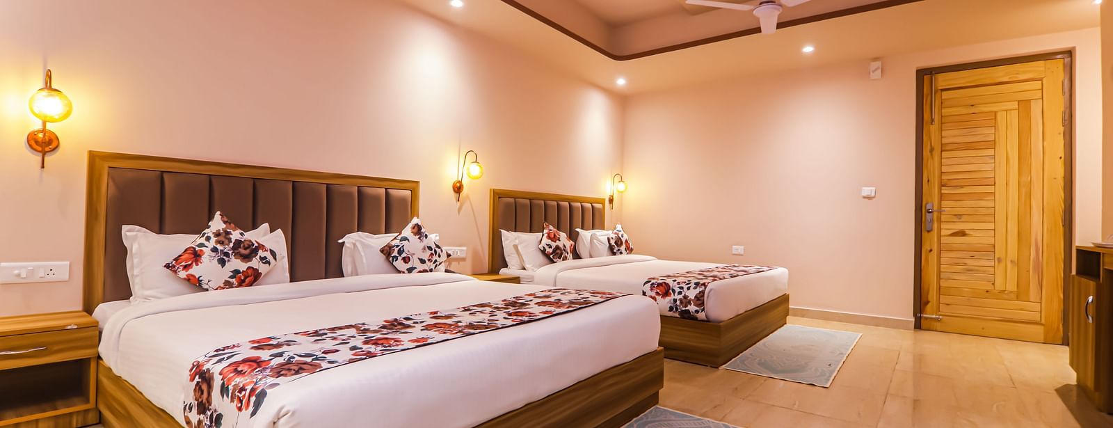 A bedroom at Vedikant Resorts The Mallard Corbett shows beds, a sofa, and a well-lit interior.