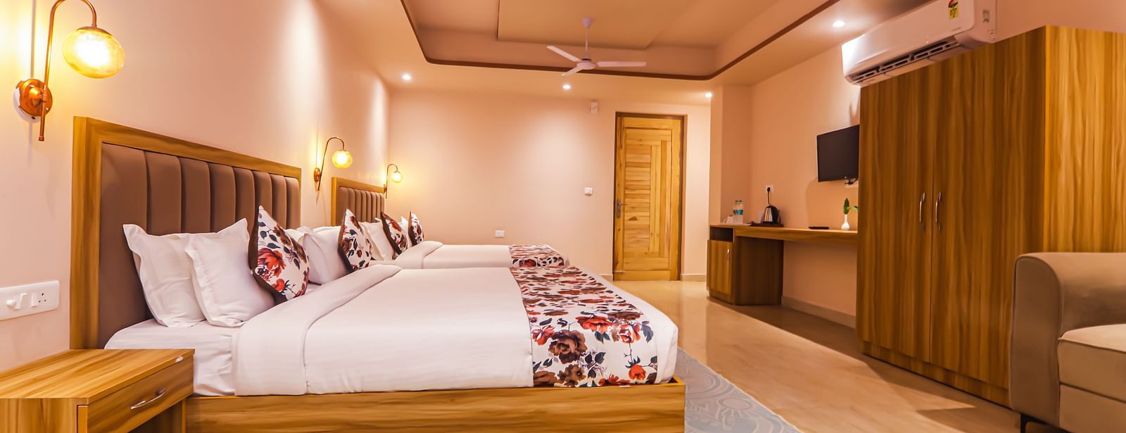 A modern bedroom at Vedikant Resorts The Mallard Corbett features beds, a seating area, and wooden furniture.