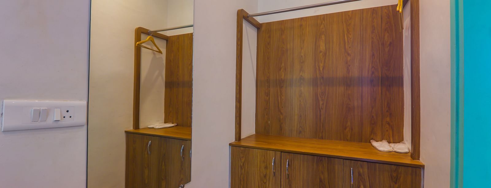 Compact dressing and wardrobe area at Vedikant Resorts The Mallard Corbett with a large mirror and wooden finish.