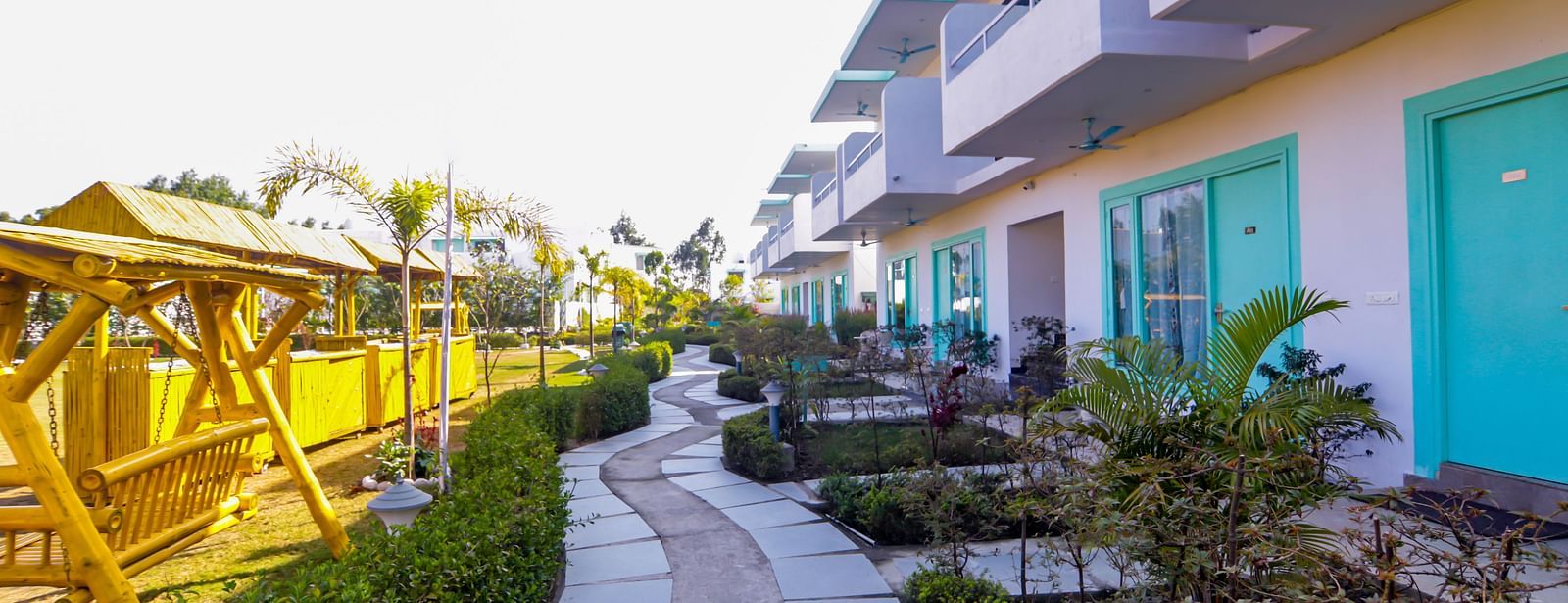 Curved walkway lined with lush gardens leading to the rooms at Vedikant Resorts The Mallard Corbett.