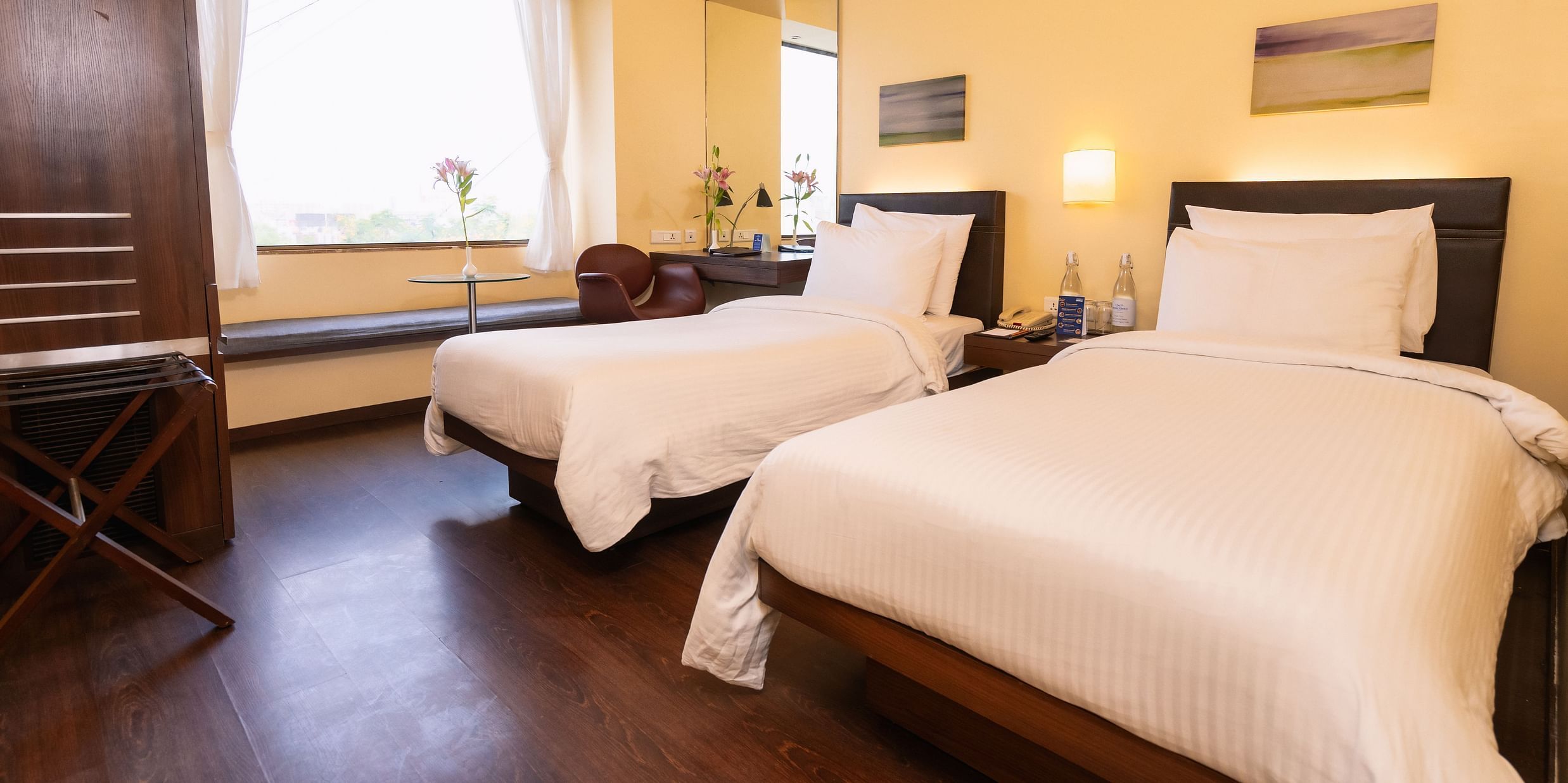 A side view of the executive bed with  comfy twin beds and a window with a view at Marasa Sarovar Portico, Rajkot