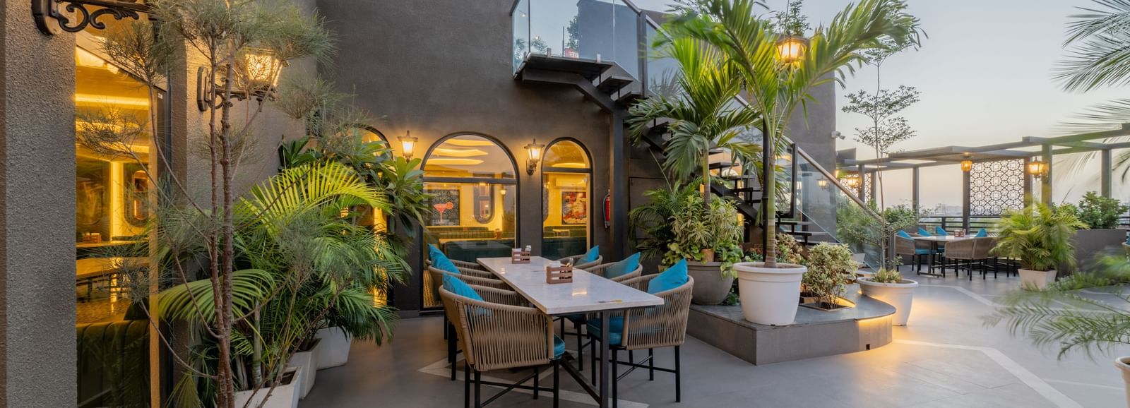 Cosy outdoor seating near arched window and tropical plants at Hotel Highway King, Jaipur.