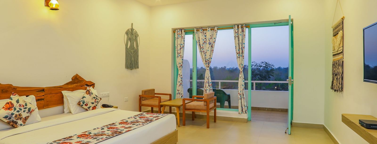 A comfortable bedroom at Vedikant Resorts The Mallard Corbett offers a bed, seating, and access to a balcony.
