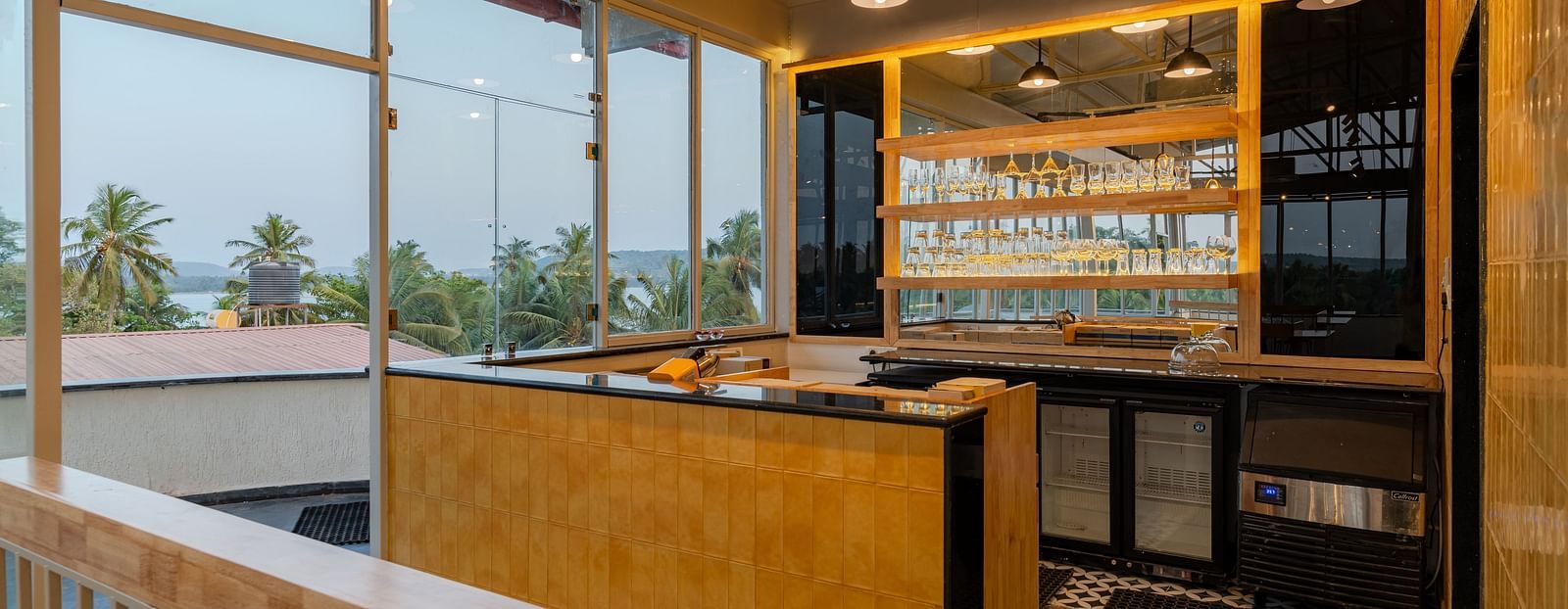 Interior of a contemporary cafe with bar stools and a window view. at Bedzzz Xclusiv Morjim, Goa