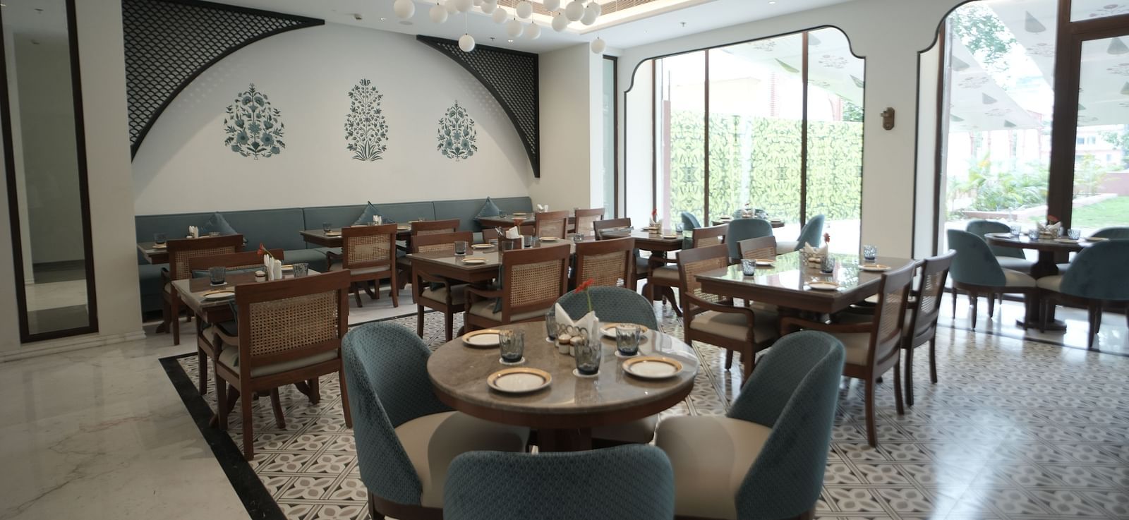 A brightly lit dining area with ample of natural lighting coming from the huge windows in the corner at Bhagirathi by RDB Atishay.