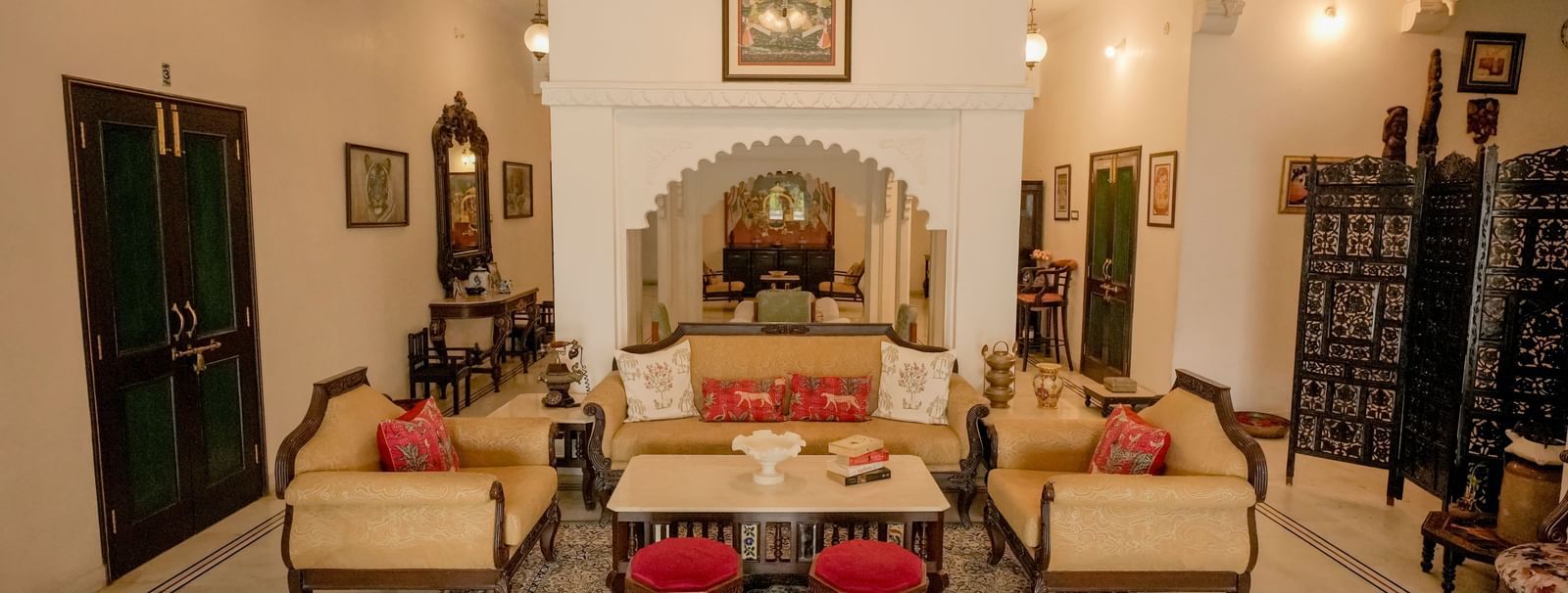  A cozy and elegant drawing-room in Mahendra Niwas, featuring twin-cushioned sofas, a central coffee table, and red ottomans.