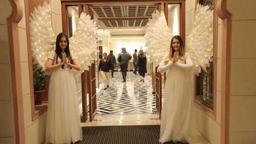 An image of two women dressed as a fairy with wings are standing at the entrance of a hall at Heritage Village Resorts & Spa