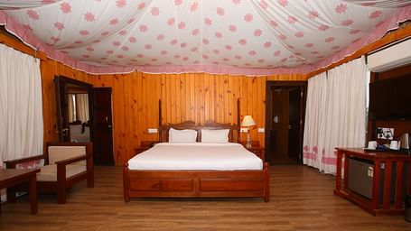 Spacious Luxury Wooden Tent with a king-sized bed and a corner cupboard at Aanandam Resort & Spa