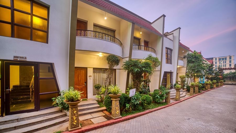 Front exterior view of the Ilara Hotels & Spa, OMR, Chennai with red tiled roofs and green landscaping, showing the main entrance driveway.