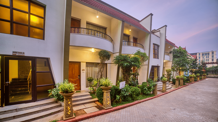 Front exterior view of the Ilara Hotels & Spa, OMR, Chennai with red tiled roofs and green landscaping, showing the main entrance driveway.