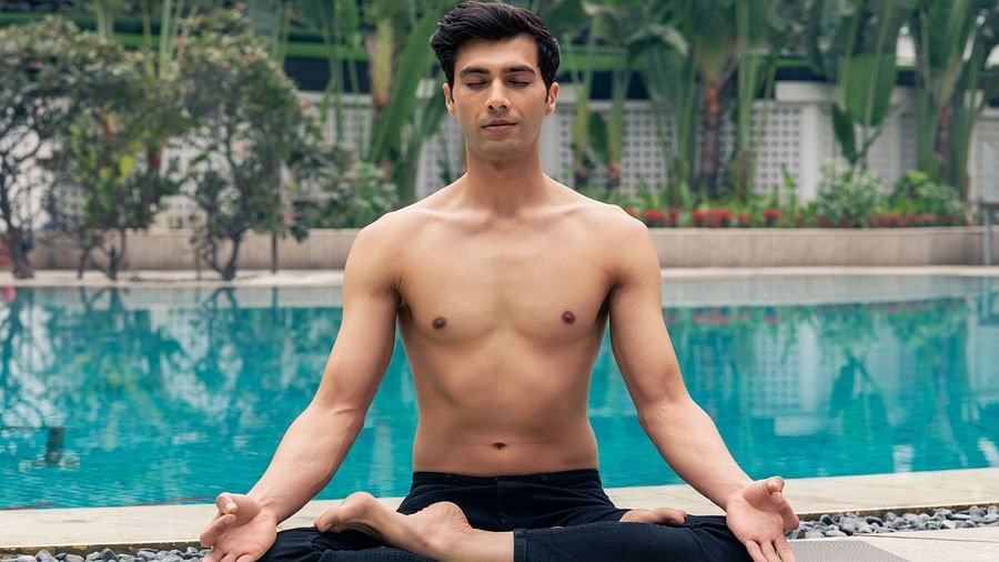 An image of a person performing yoga in front of the pool - The Claridges New Delhi