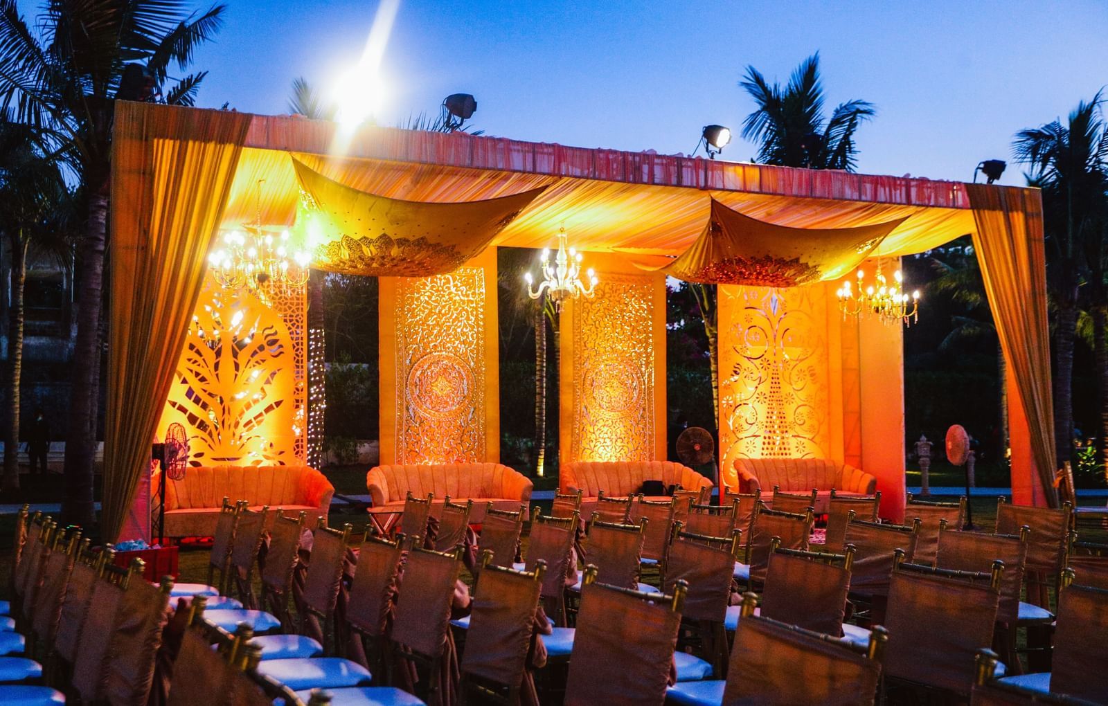 A stage draped with orange coloured cloth in the Sundarabagh lawn at Kaldan Samudhra Palace featuring chairs in theatre seating arrangement