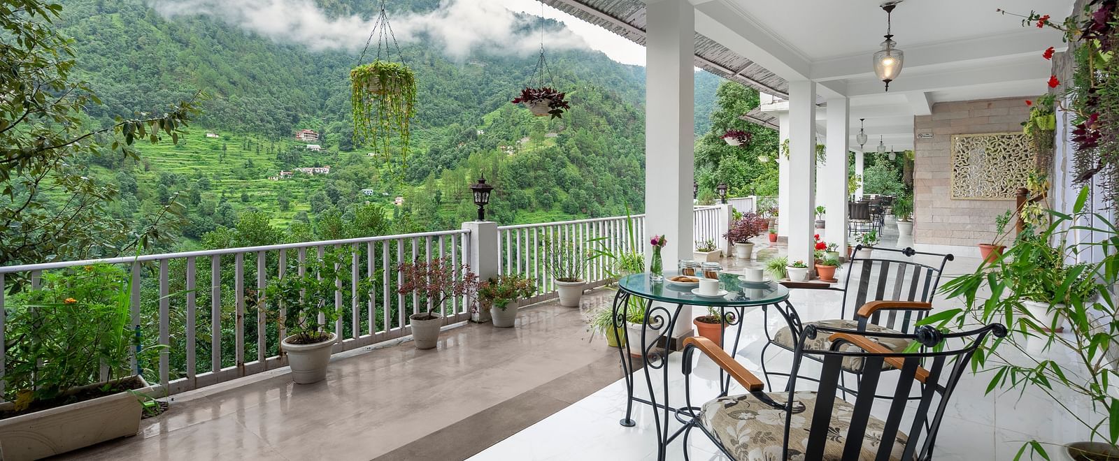 Open-air veranda with seating and potted plants overlooking forested hills, at BluSalzz Collection - Suvaasa Resort, Ramgarh.