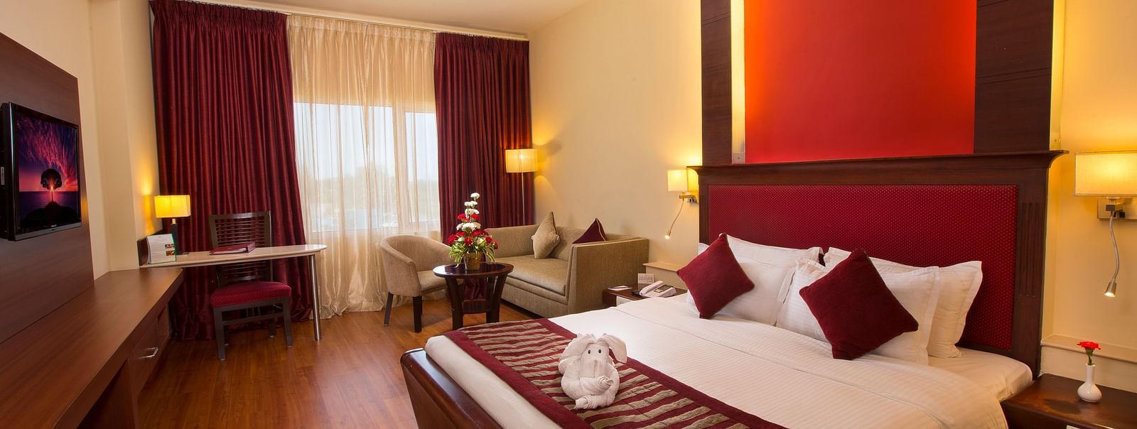 A well-appointed room with a comfortable bed, seating areas, a TV, and lamps.