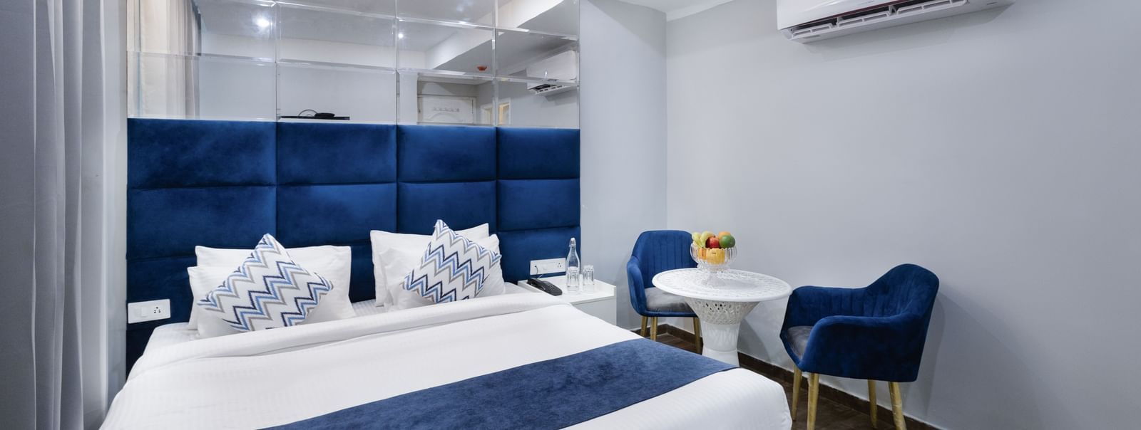 Royal blue palette bedroom with king-sized bed and cosy sitting area at Hotel Downtown17, Chandigarh.