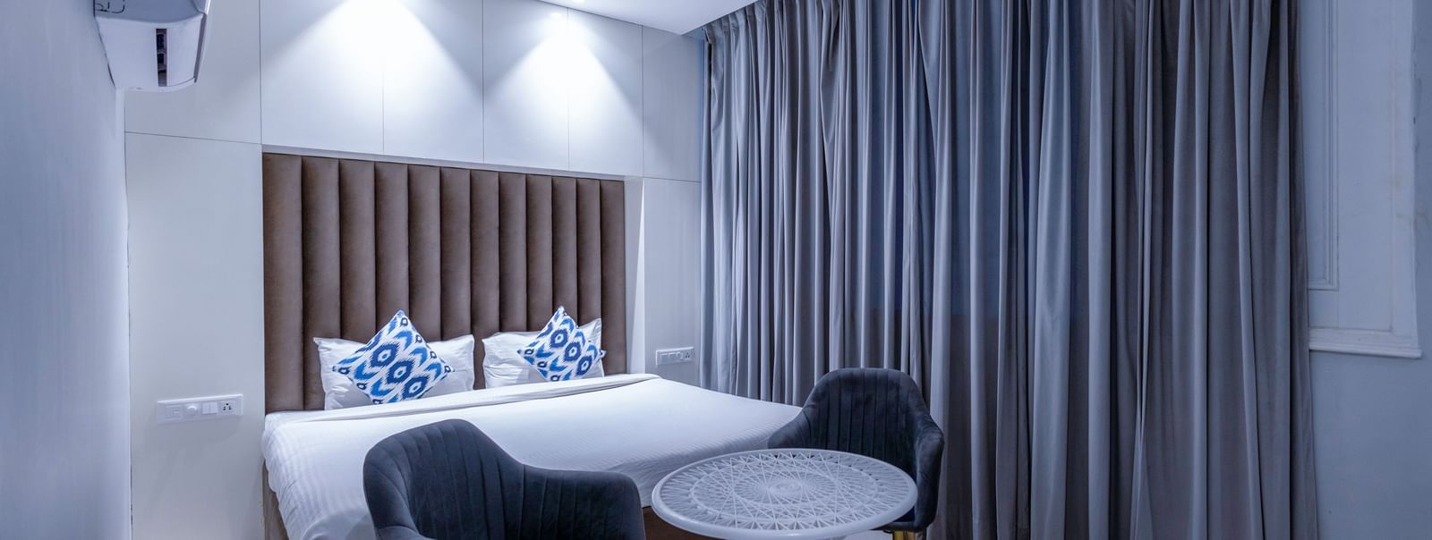 Bright modern bedroom with sleek curtains and a chic round table setup at Hotel Downtown17, Chandigarh.
