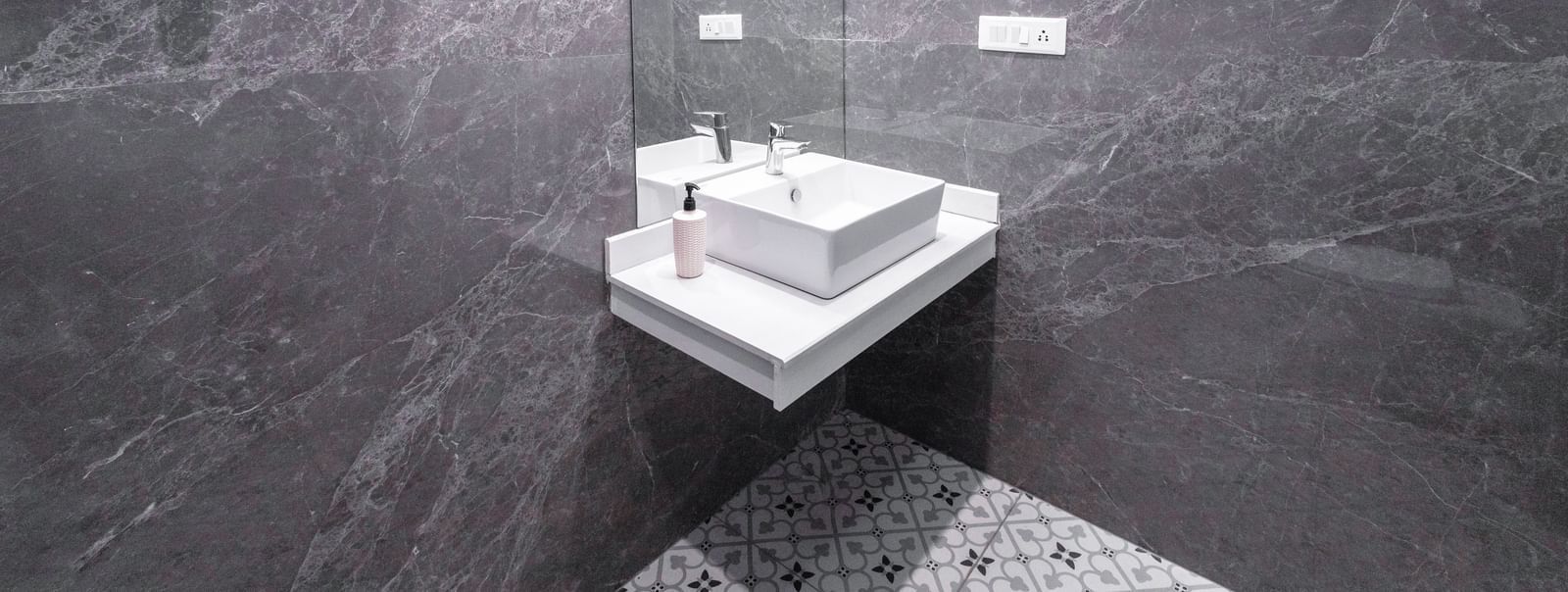 A bathroom with a white sink, grey walls and marble flooring at Hotel Downtown17, Chandigarh.
