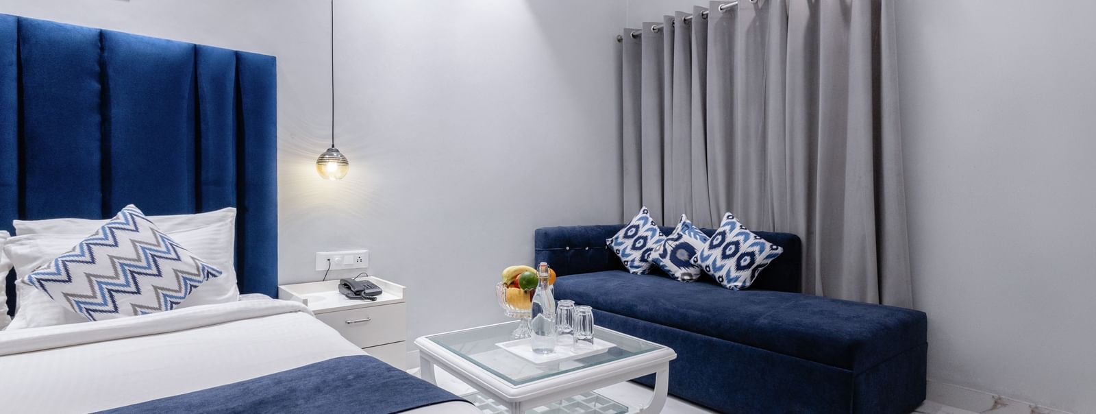 Hotel bedroom at Hotel Downtown17, Chandigarh with white lighting, sofa, table and royal blue palette.