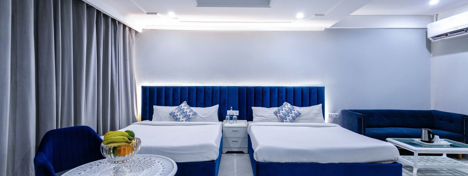 Family room with twin beds and a dark blue palette with sitting area at Hotel Downtown17, Chandigarh.