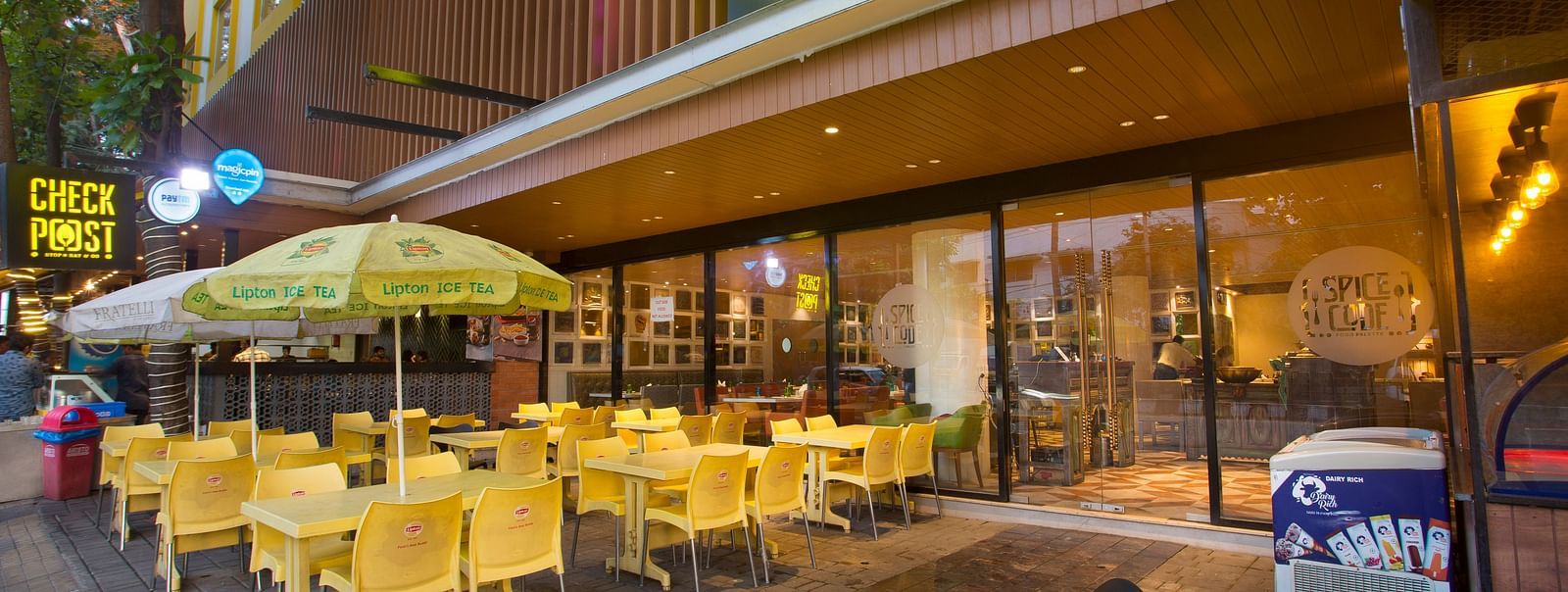 an outdoor restaurant with umbrellas mounted on the tables to provide shade - Hotel Fountain Tree By TGI - JP Nagar, Bangalore