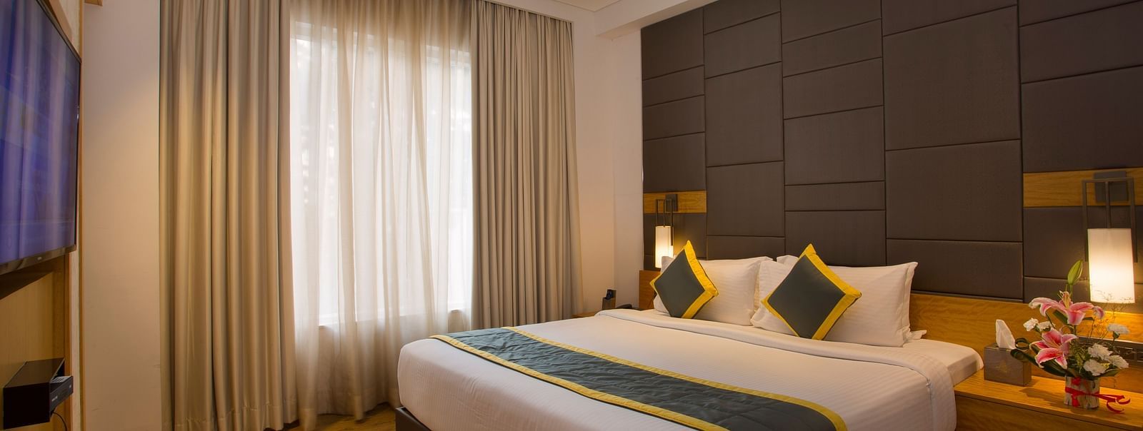 view of a bedroom with a large bed facing a television and two side drawers, one on each side of the bed - Hotel Fountain Tree By TGI - JP Nagar, Bangalore
