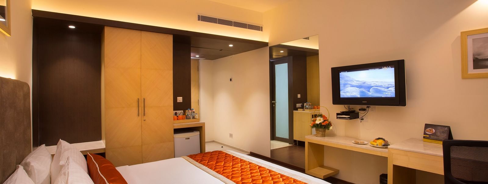 A comfortable hotel room with modern amenities, a large bed, a TV and a work desk with a chair - Hotel Langford Keys by TGI, Shanti Nagar