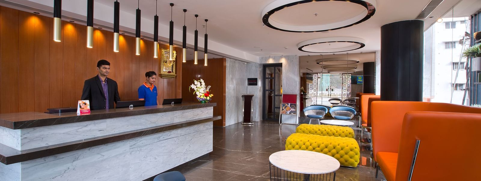 A modern hotel reception area with bright orange and yellow seating, a dark wooden front desk and pendant lights - Hotel Southend by TGI - Bommasandra, Bangalore
