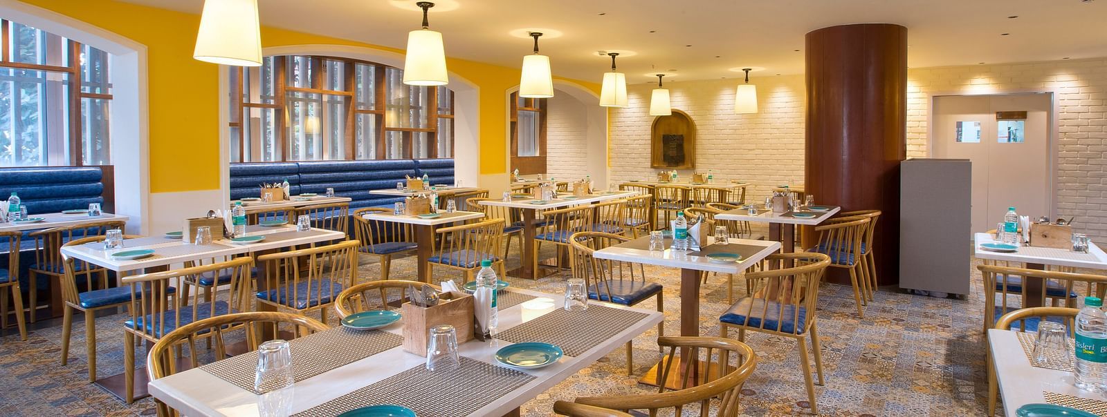 A spacious and brightly lit restaurant with wooden chairs, patterned tile floor and large windows - Hotel Southend by TGI - Bommasandra, Bangalore