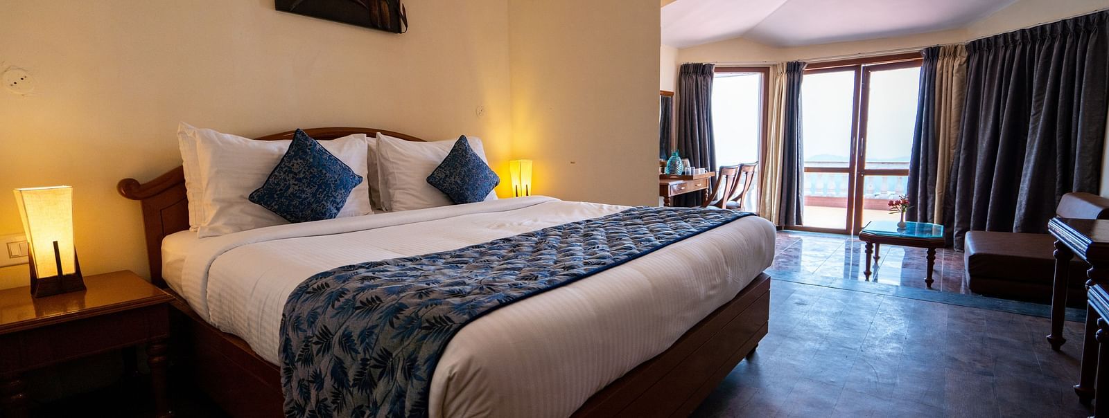 comfy bed with blue duvet and pillows at La Montana By TGI, Ooty