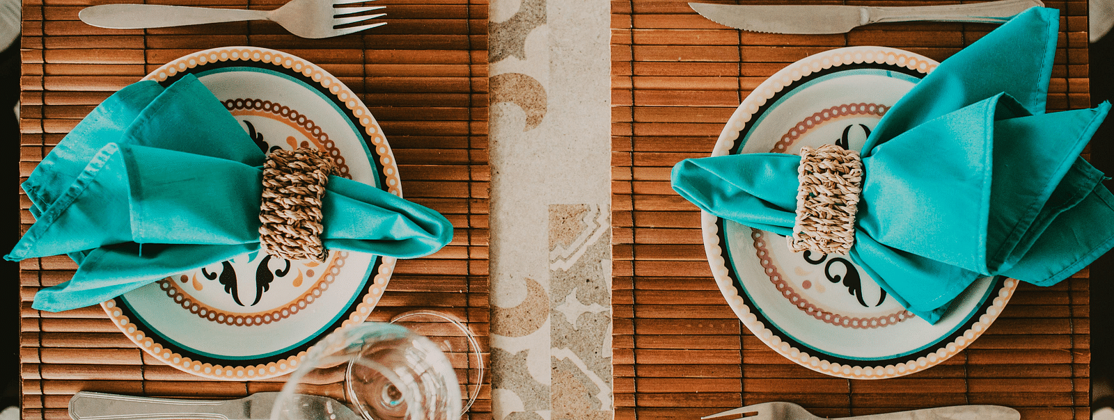 An image of a restaurant table with plates, cutlery, and glasses laid on it
