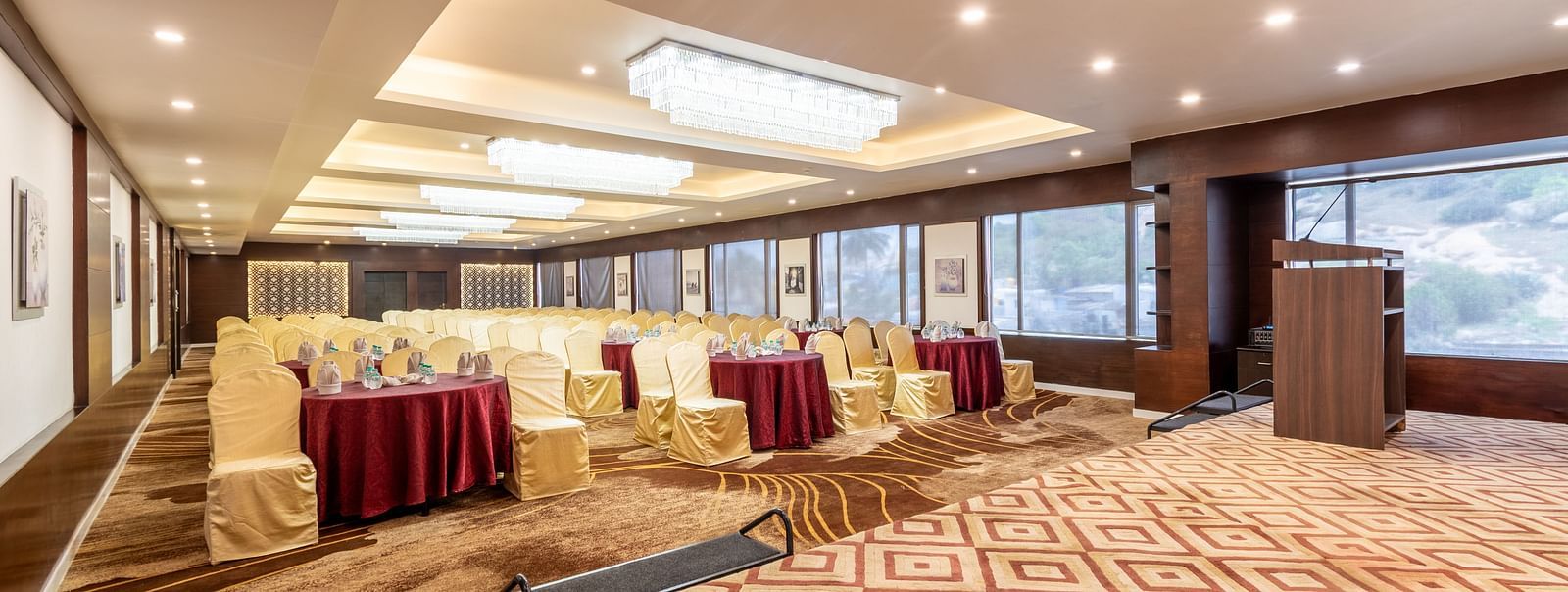 Versatile banquet space with podium and large windows, set for a business meeting or seminar