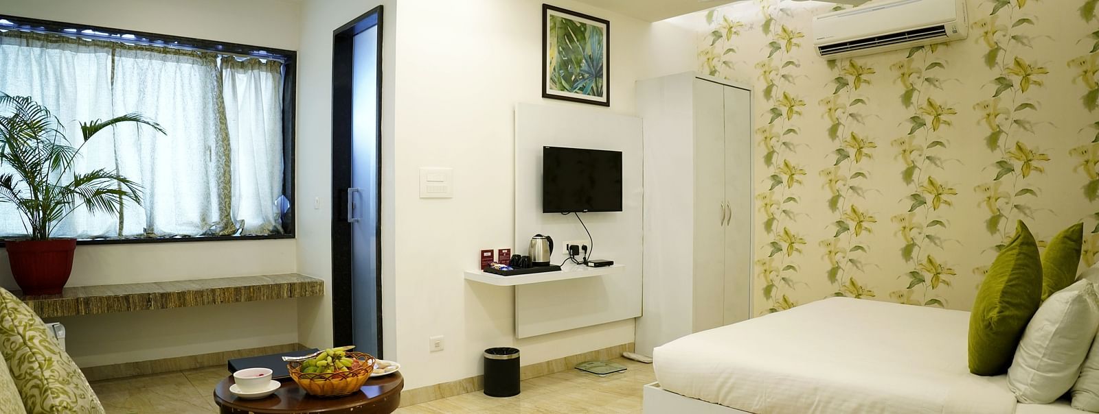 A serene bedroom setup with a large window and a white and green colour scheme - TGI Insignia, Bhopal