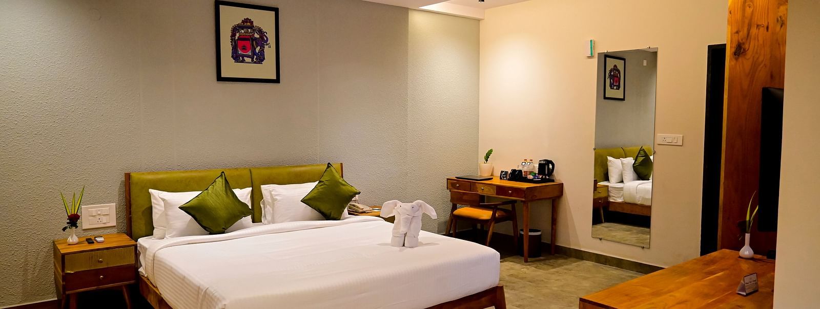 Hotel room with a large bed, olive green pillows, a unique black and white rug, and wooden furniture at TGI Livancia Hillside, JC Nagar, Mysore