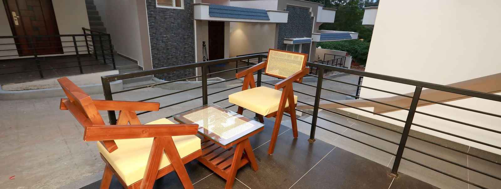 Close up of the 2 arm chairs kept in the outdoor seating area of Nature Luxury Room overlooking the pathway beside it connecting other lodges at WOW Naturefull Resorts, Yercaud.