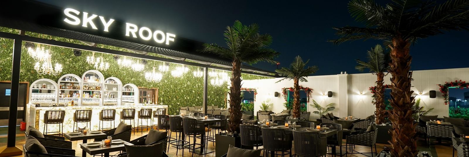 A wide angle shot of Sky Roof during the night with various tables arranged in an open air space at M2 Square by Monday Premium.