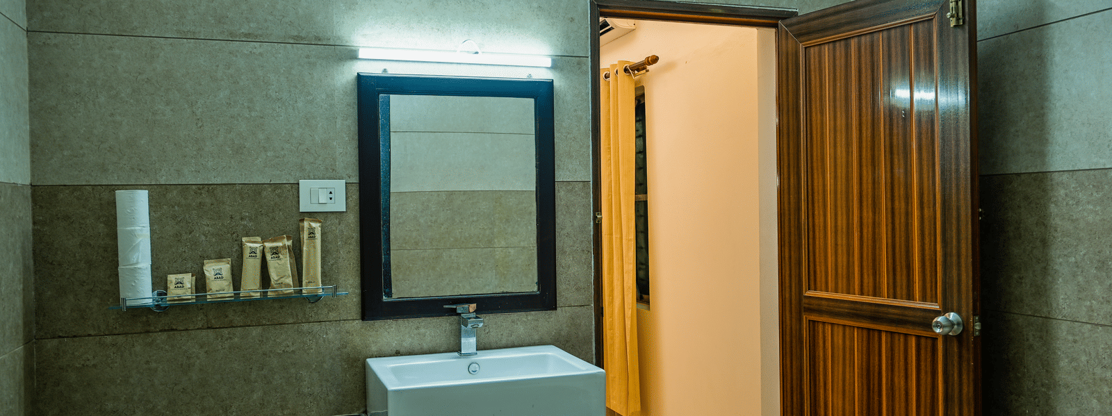 A bathroom vanity at Ayur On The Beach Nattika with a counter-top washbasin, mirror, and a laminated door.
